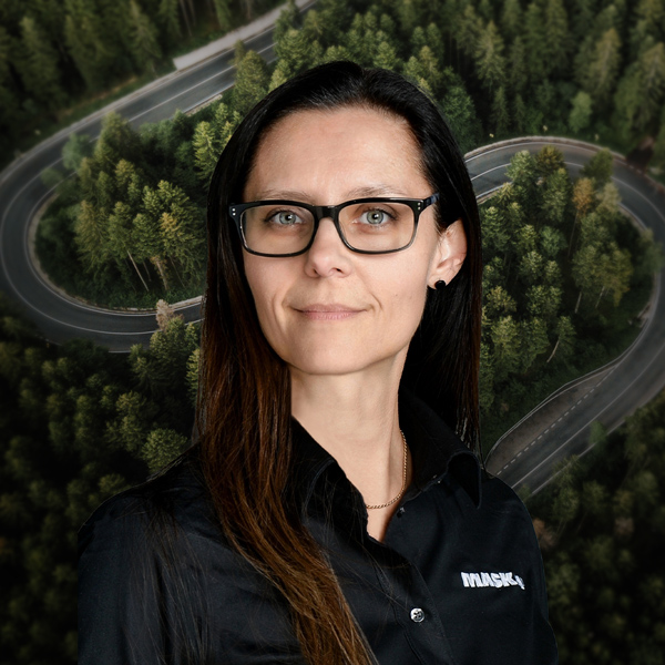 Femme portant un chandail noir MASKA, devant un décor aérien de route sinueuse traversant une forêt.