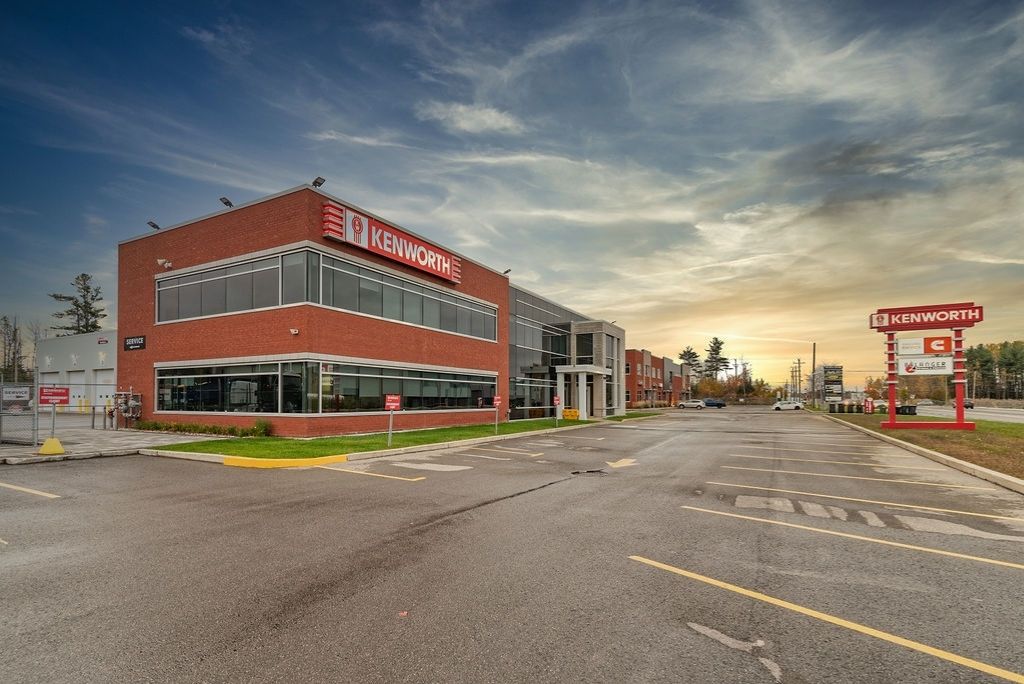 Façade de la succursale Kenworth MASKA Mirabel, offrant la vente et le financement de camions lourds Kenworth ainsi que des services de pièces, d’entretien et de réparation. Exterior of the Kenworth MASKA Mirabel dealership, offering Kenworth heavy-duty truck sales and financing, as well as parts, maintenance and repair services.