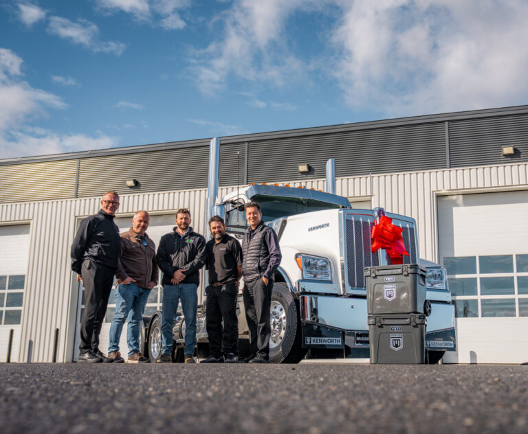 Livraison du Kenworth W990 fabriqué au Québec à Groupe JMV, en présence des représentants de l’entreprise et de l’équipe MASKA, devant le camion neuf. Delivery of a Quebec-built Kenworth W990 to Groupe JMV, with company representatives and the MASKA team standing in front of the new truck.
